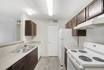 A kitchen with white appliances and brown cabinets.